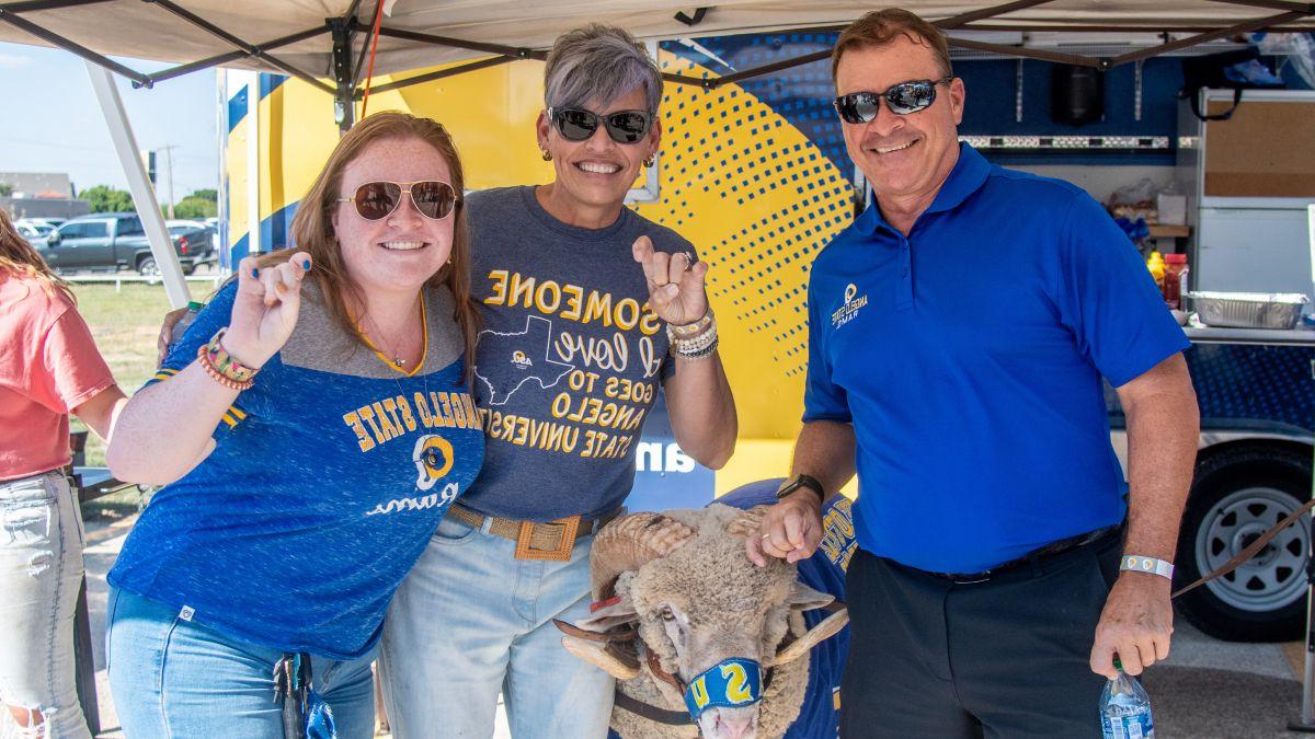Parents taking a photo with Dominic, the live ram mascot, at a Ram Jam tailgate