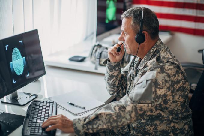 一个美国士兵独自坐在办公室里用电脑.