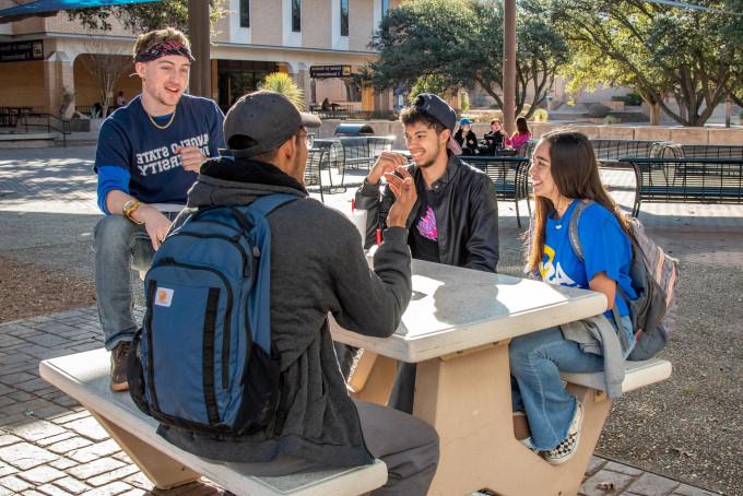 Students sitting at a table outside laughing.