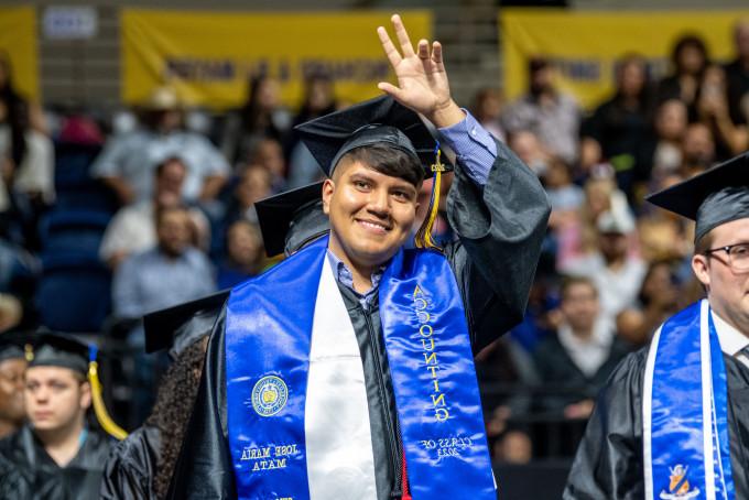 A student waving to the crowd at graduation